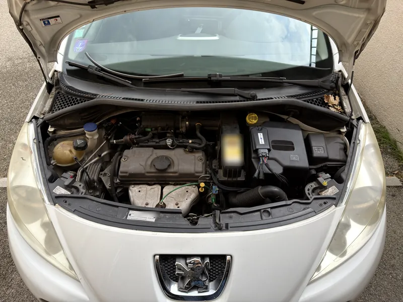 Compartiment moteur de la Peugeot 207 1.4 après la pose du kit E85 : boîtier eFlexBlue fixé sur le bac de batterie, faisceau gainé et plaque d'identification du kit