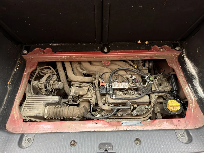 Moteur arrière de la Renault Twingo III, accessible par la trappe sous le plancher du coffre, après la pose du kit E85 : faisceau raccordé sur les injecteurs et plaque d'identification du kit